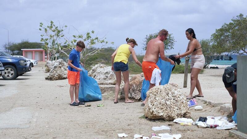 Turista i siudadanonan ta pone man huntu i limpia Te Amo Beach despues di opservá kantidat di shushi benta abou